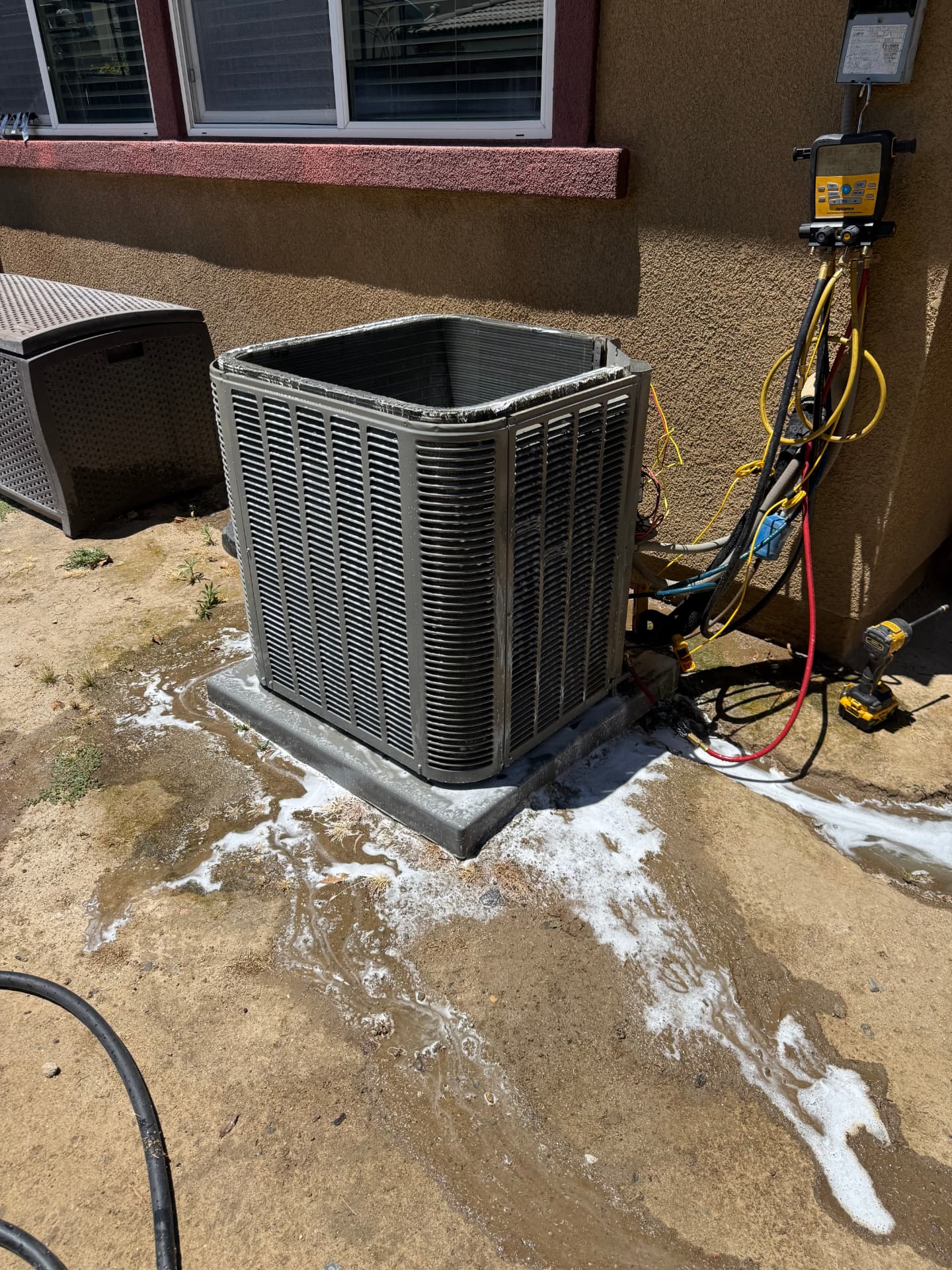 Outdoor heat pump condenser being serviced at a residential home